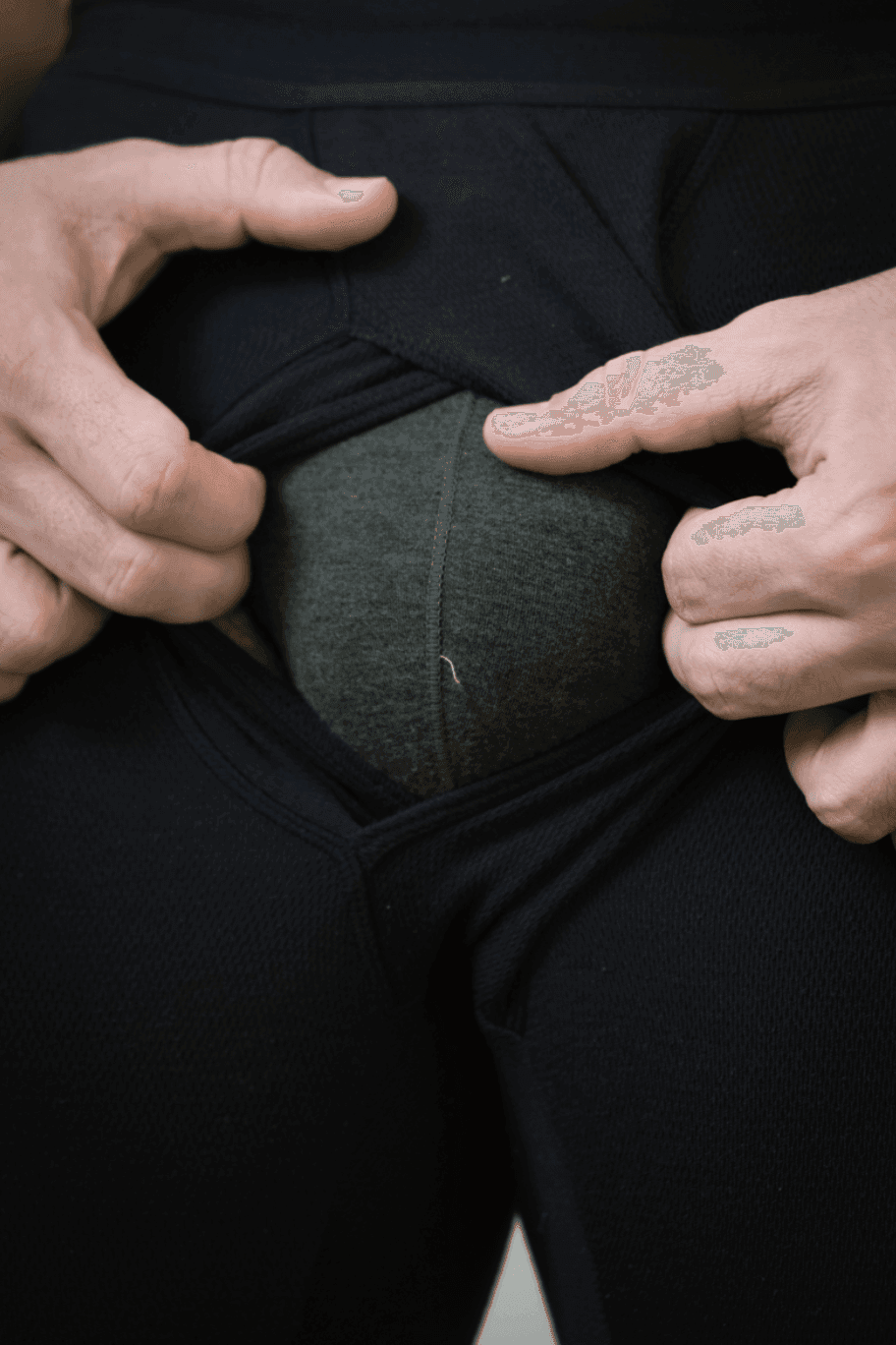 Hands pulling fabric, revealing a bulge