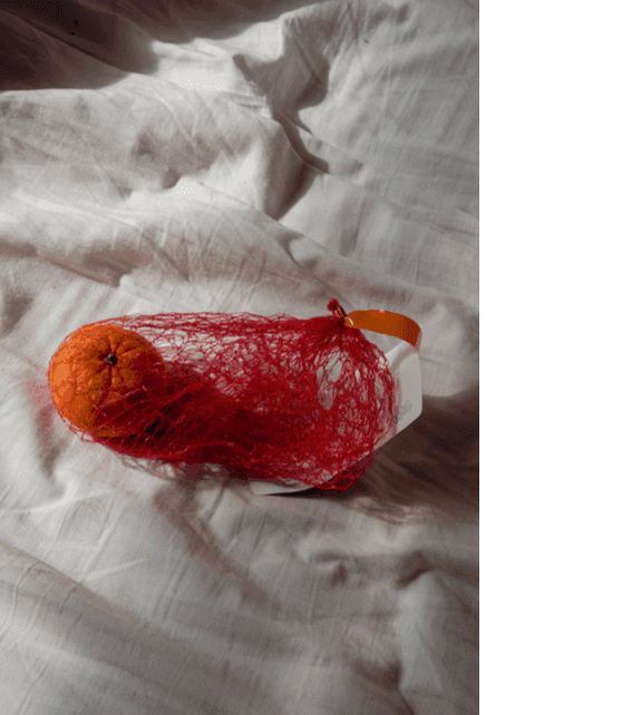 Tangerine wrapped in net on a bed